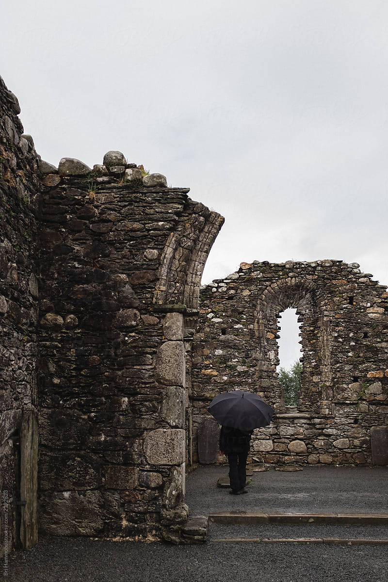 Person with umbrella in church ruins