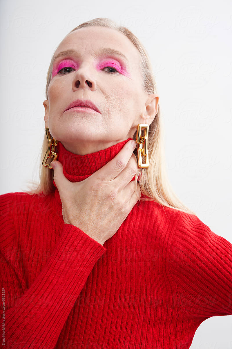Portrait of an older woman in a red turtleneck on a white background