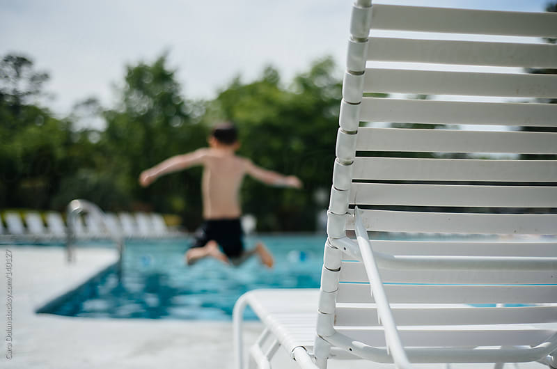 Boy jumps into a swimming pool by Cara Dolan Stocksy United