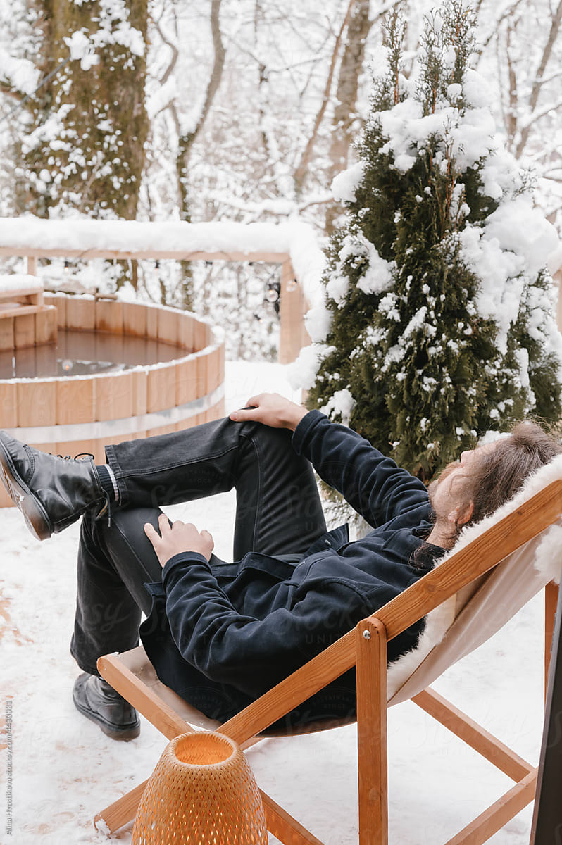 Man relaxing in deckchair and admiring winter forest