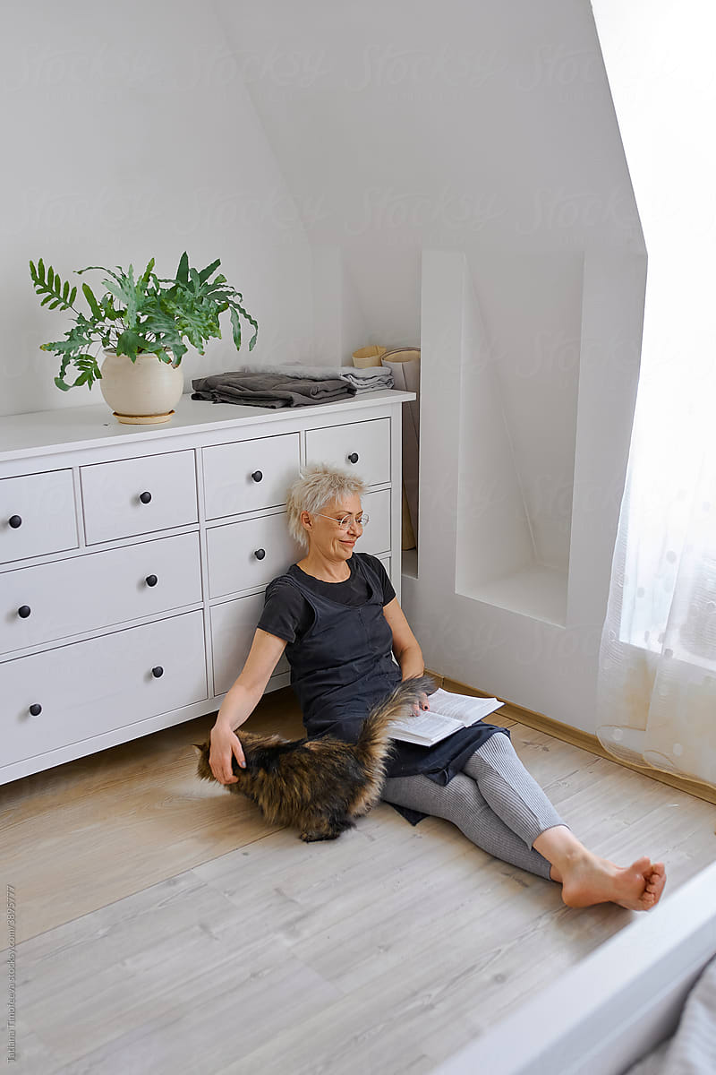 senior elderly woman petting pet cat at home bedroom