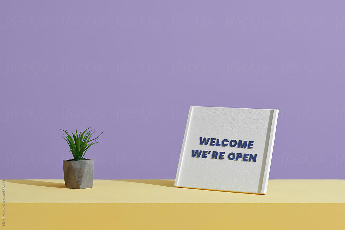 A \'Welcome We\'re Open\' sign on table of a shop