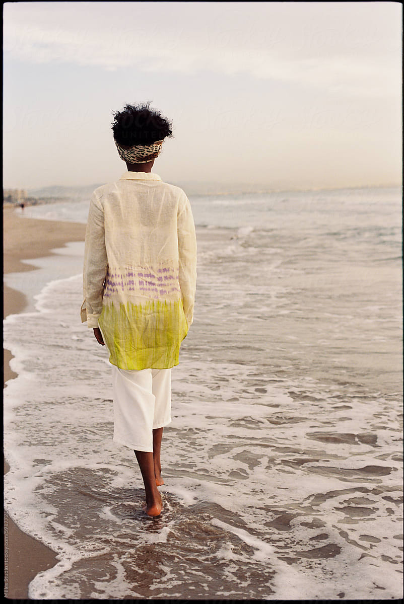 African woman strolling beach near sea