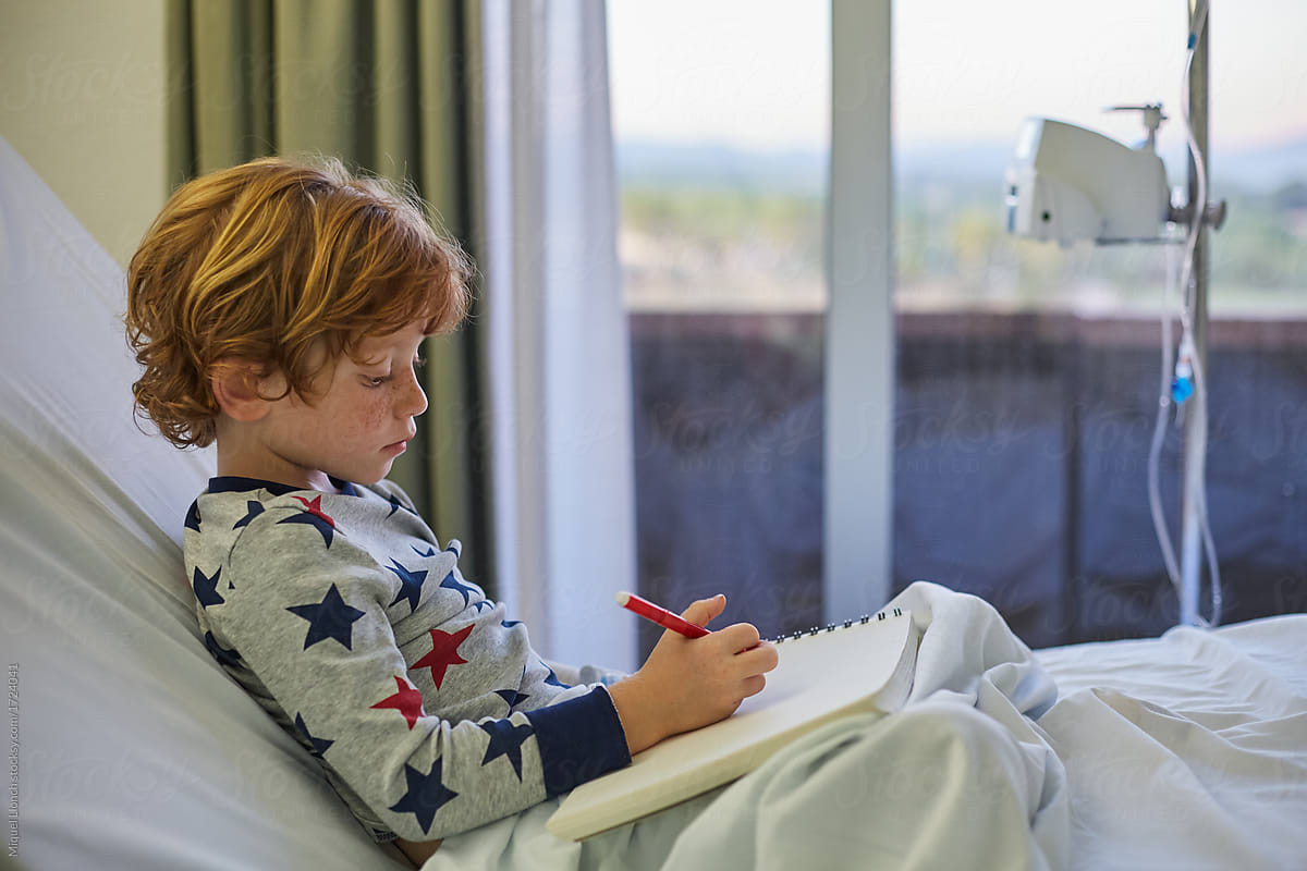 Child Patient Lying On A Hospital Bed And Drawing In A Sketchbook by