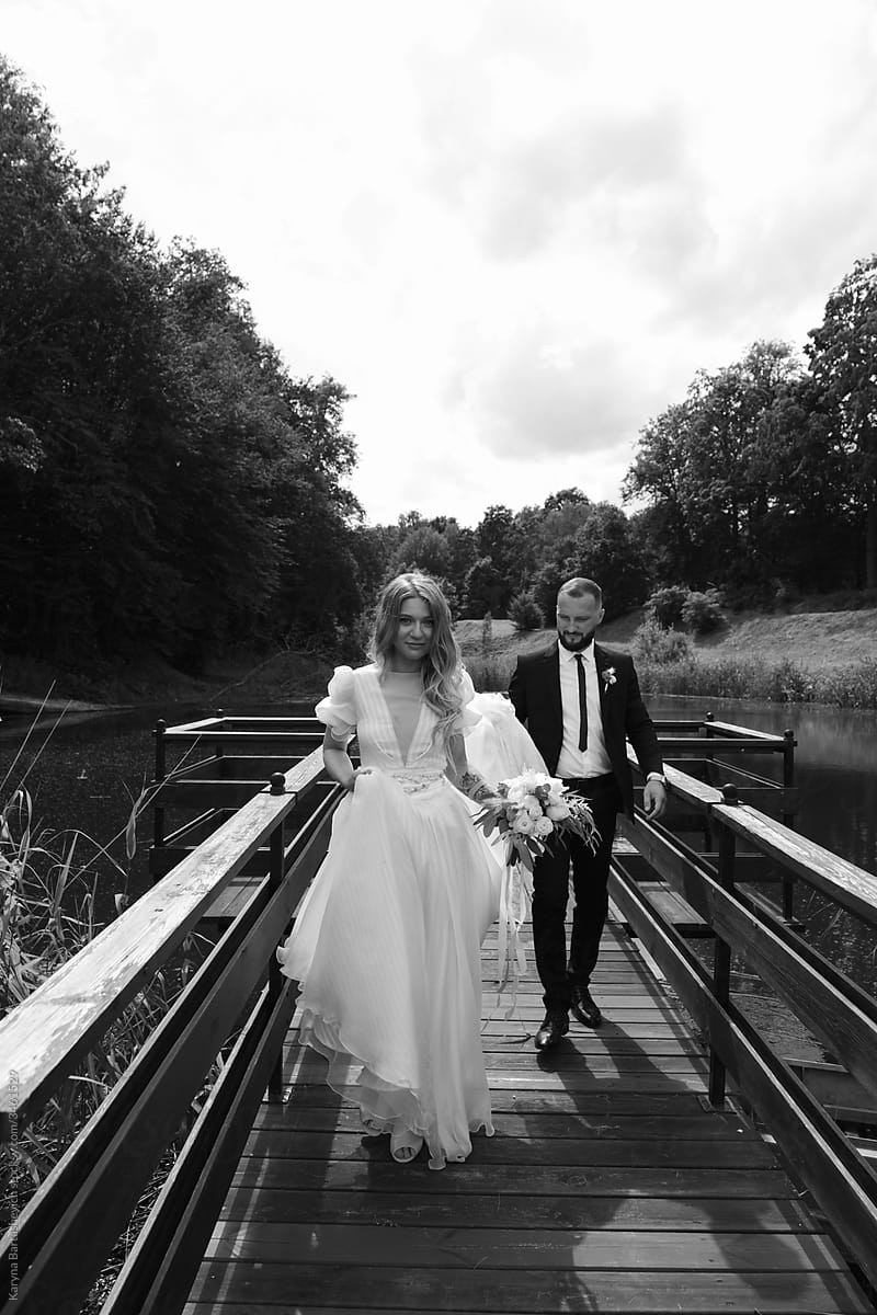 black and white photo of the bride and groom walking across the bridge after the wedding