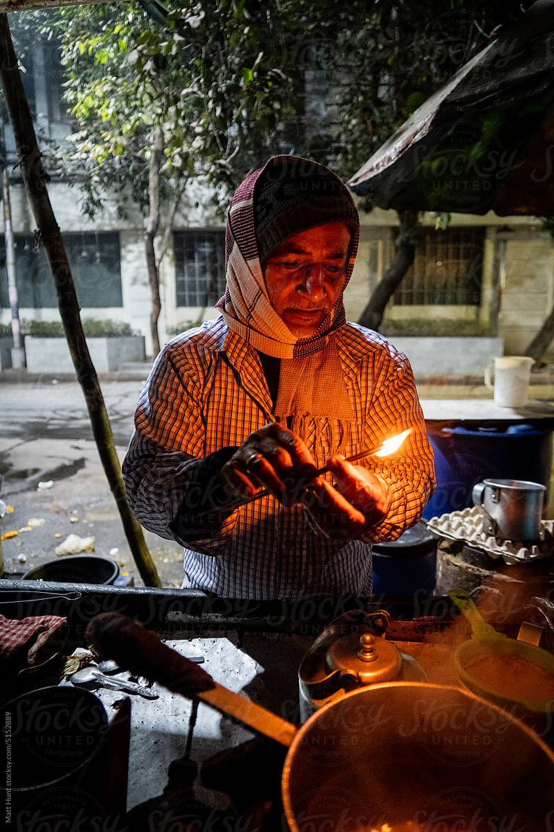 Portrait of a pushcart seller lighting incense on the street in India