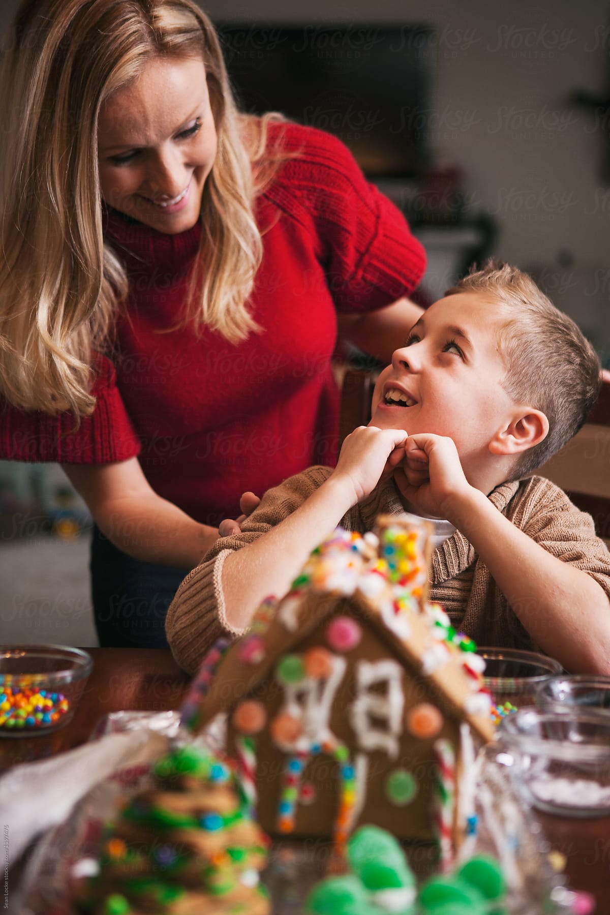 Christmas: Mother And Son Laugh During Gingerbread House Decorat