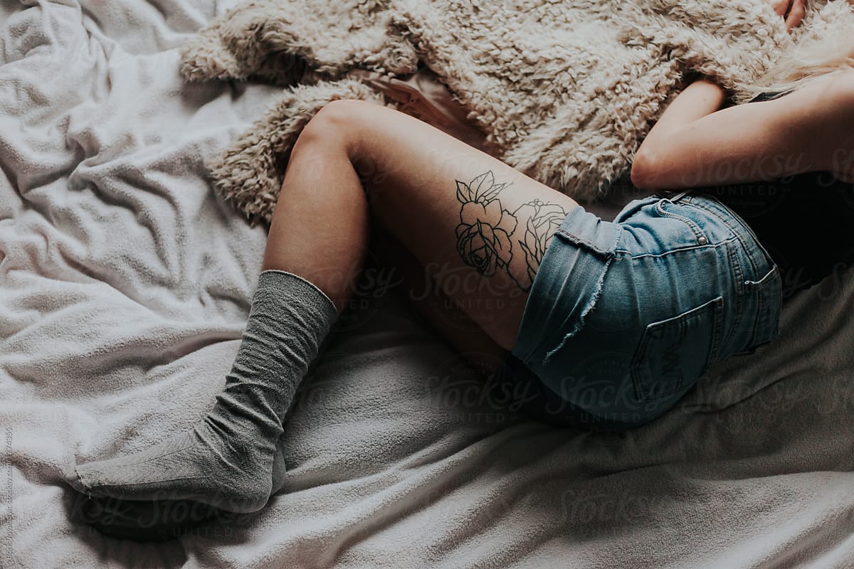 Young tattooed woman laying on bed