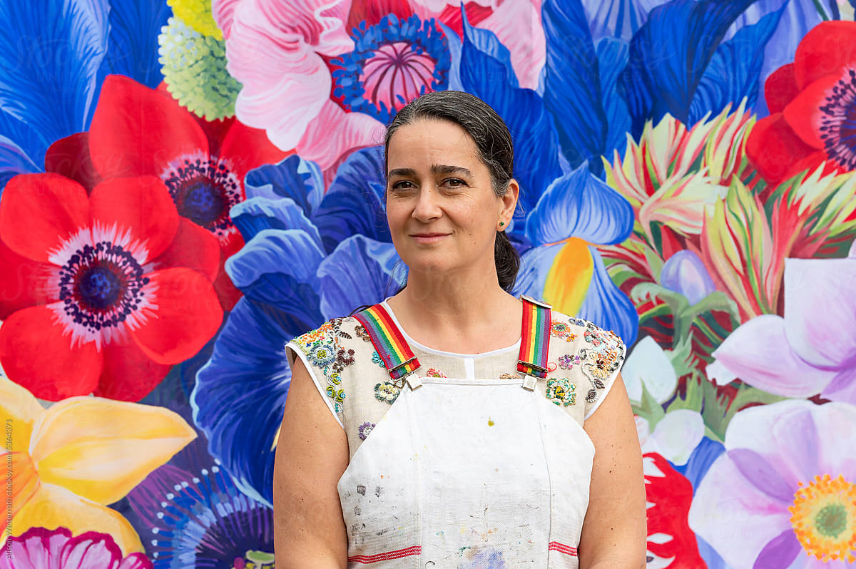 Person posing for a headshot in front of floral mural