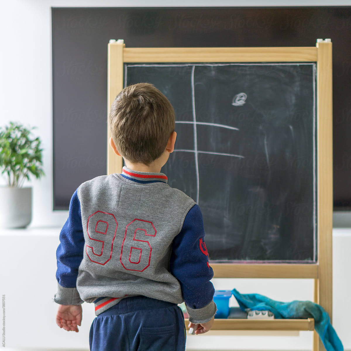 Kid writing with chalk on a blackboard in his living room