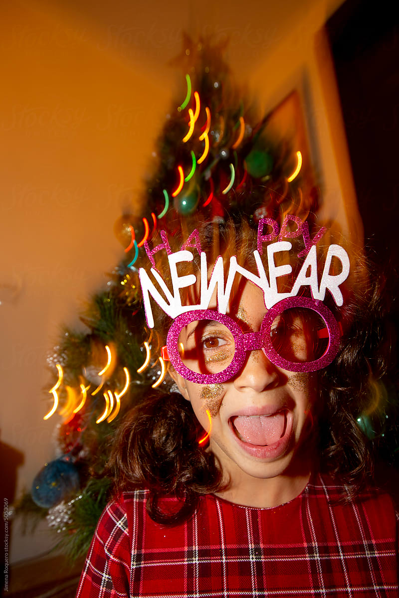 Kid making funny faces with Happy New Year party glasses