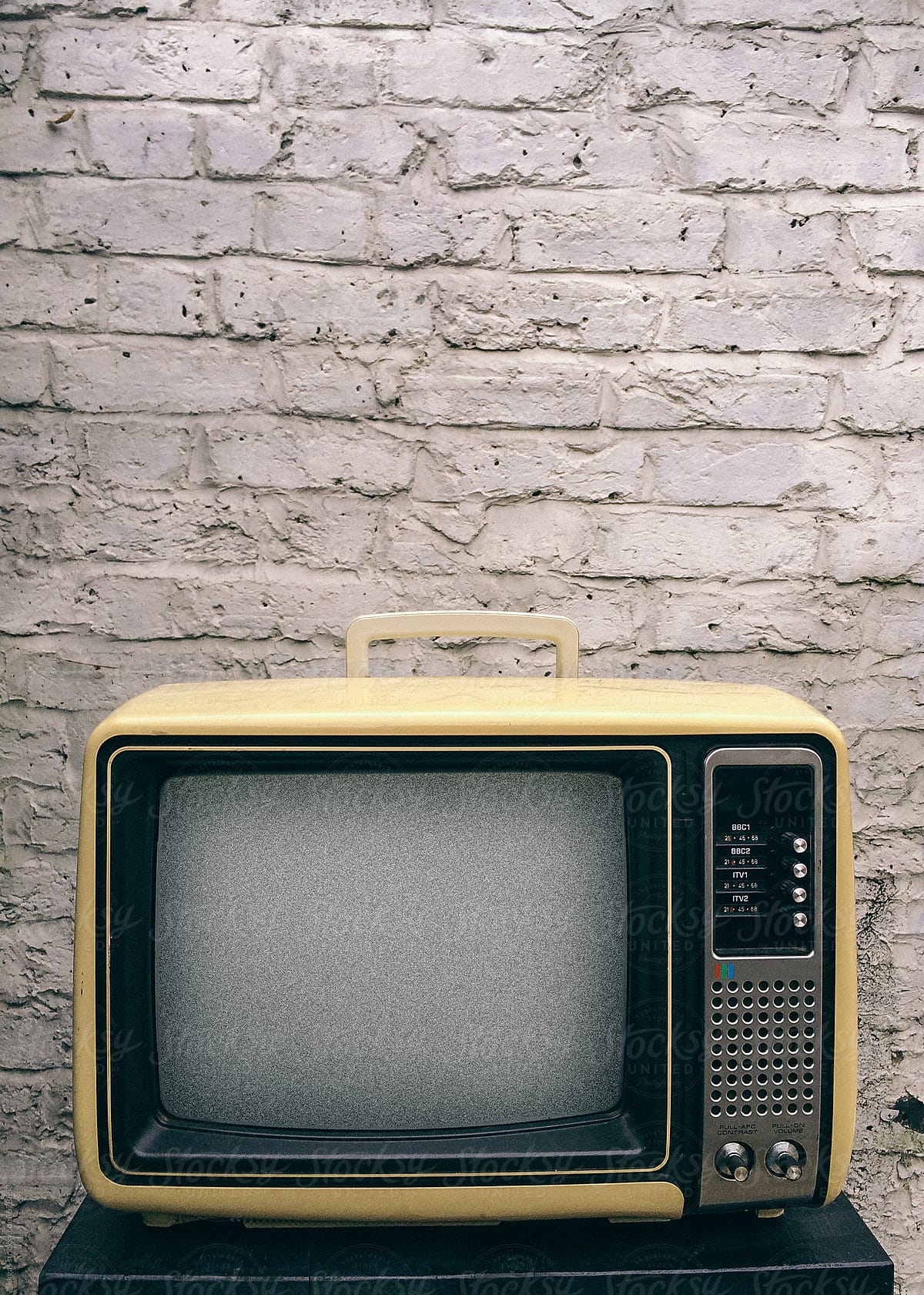 Old Television in front of brick wall