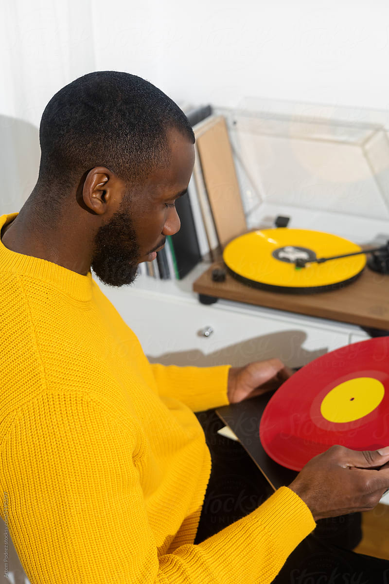 A black man in a yellow sweater listens to music