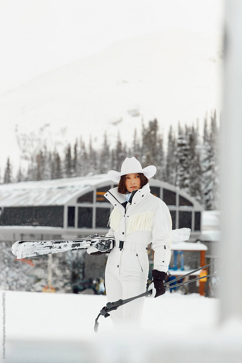 A woman in a stylish ski outfit standing with skis