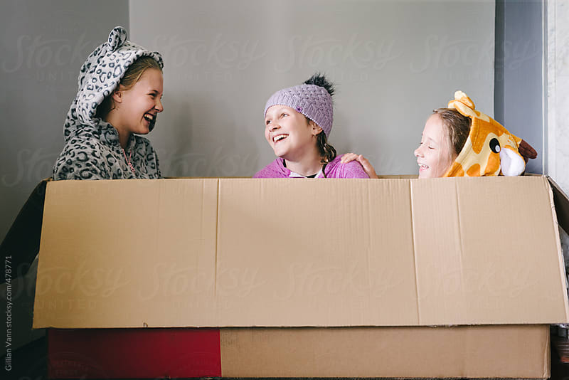 three children playing in an empty cardboard box