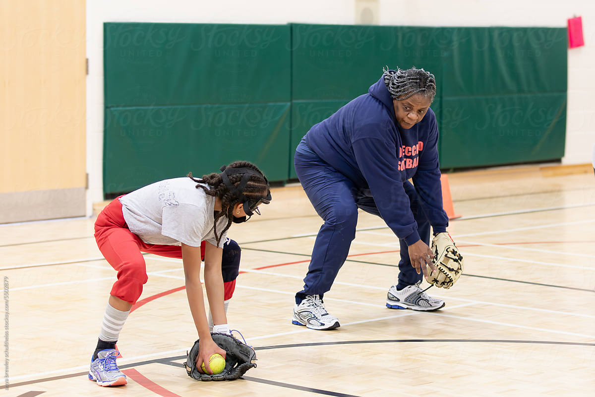 Senior woman teaching proper softball fielding technique.