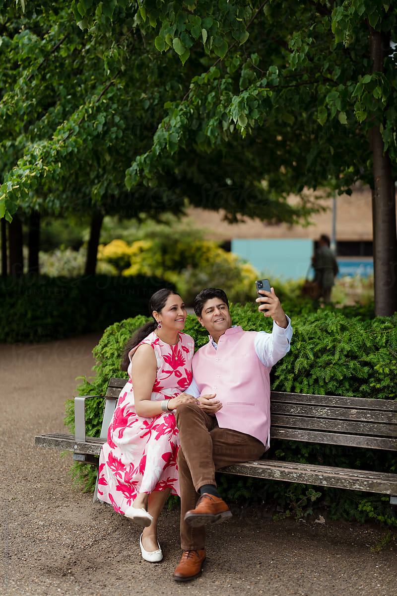 Adult couple taking a selfie with a smartphone in a city park