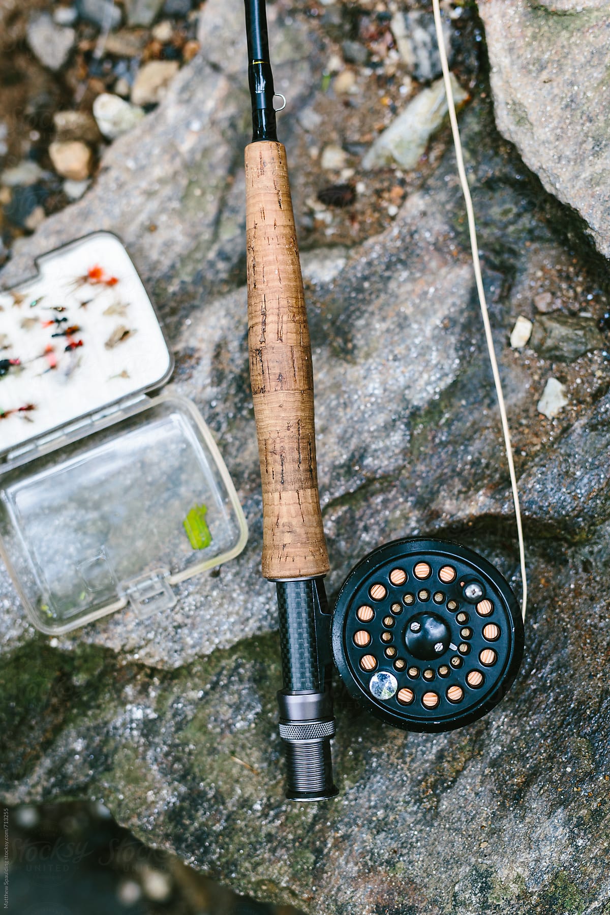 Fly fishing rod, reel and flies on river bank