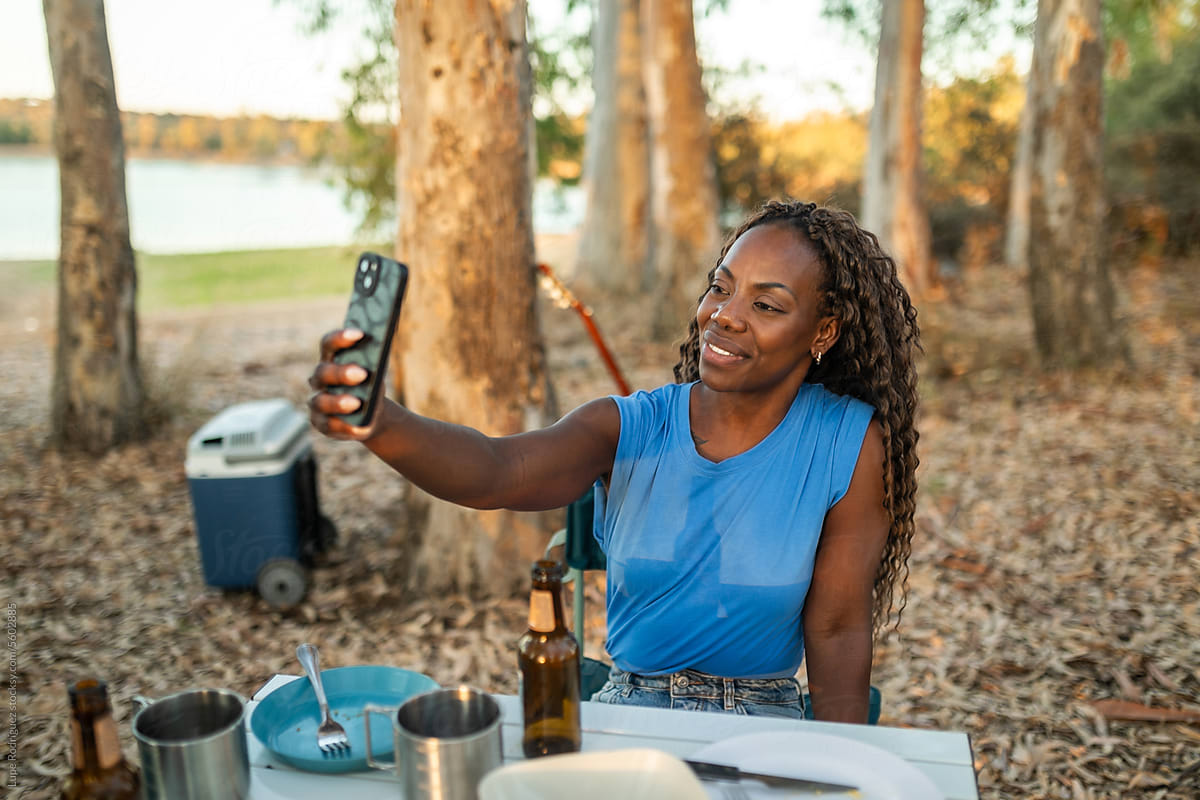 black woman camping using mobile phone