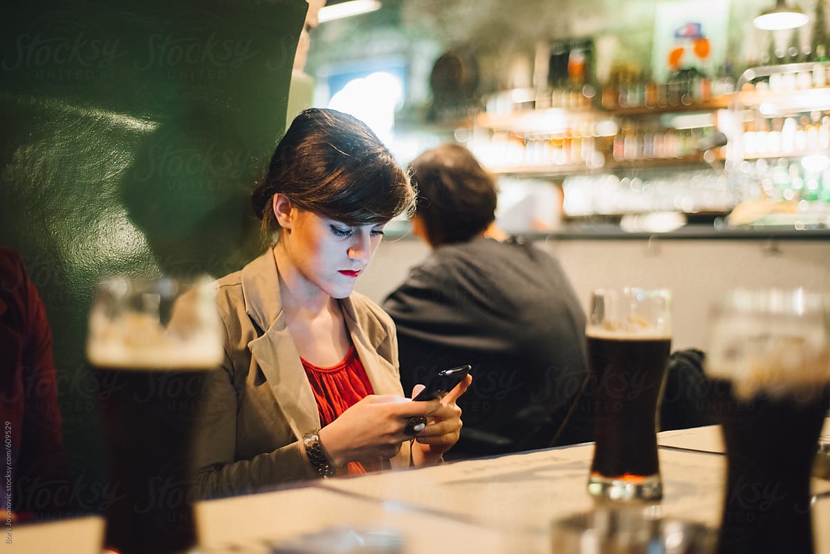 Young woman using a mobile phone in the pub