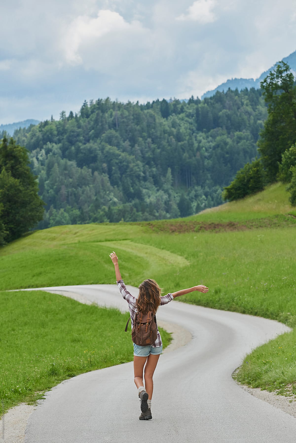 Traveller backpack happy girl dancing on scenic countryside road