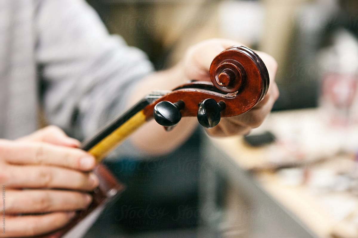 Band: Man Fiddles With Violin Tuning Pegs During Repair