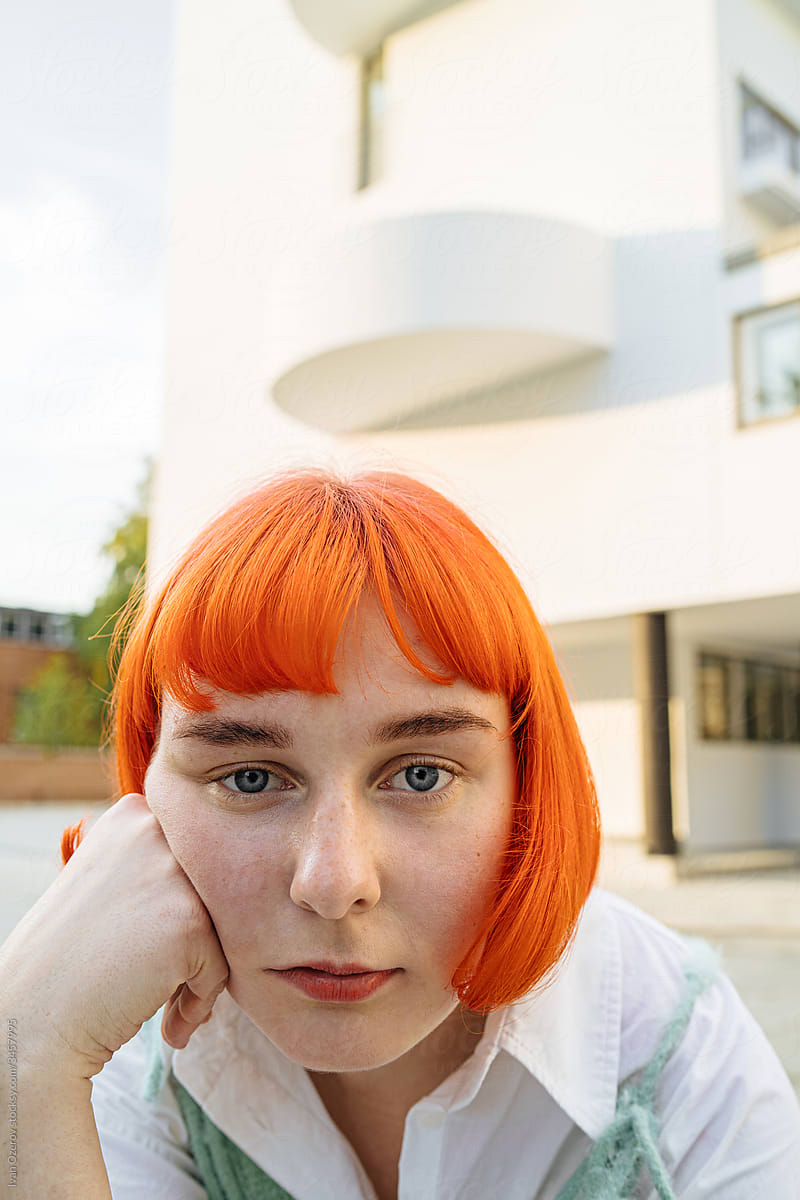 cute red-haired woman with serious face against the background of a modern building