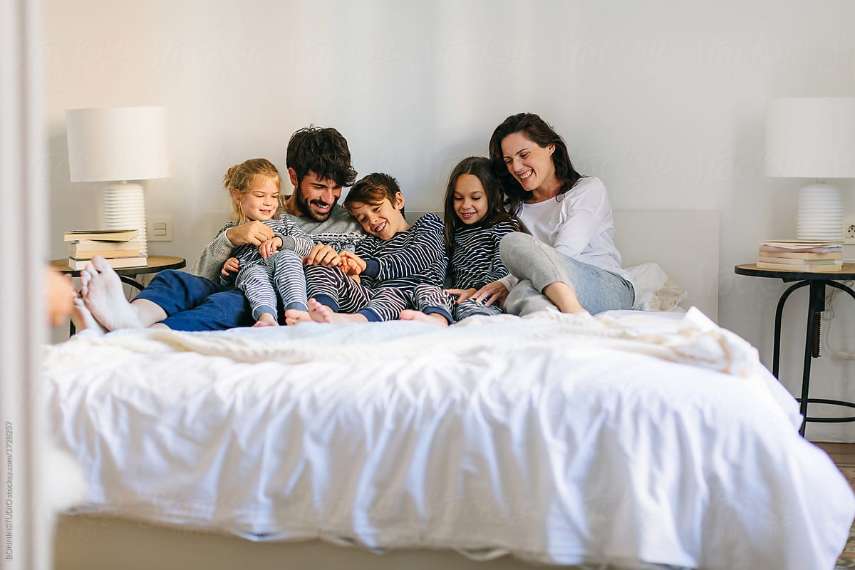 Portrait of happy family wearing pajama resting on bed. by BONNINSTUDIO -  Bed, Family - Stocksy United