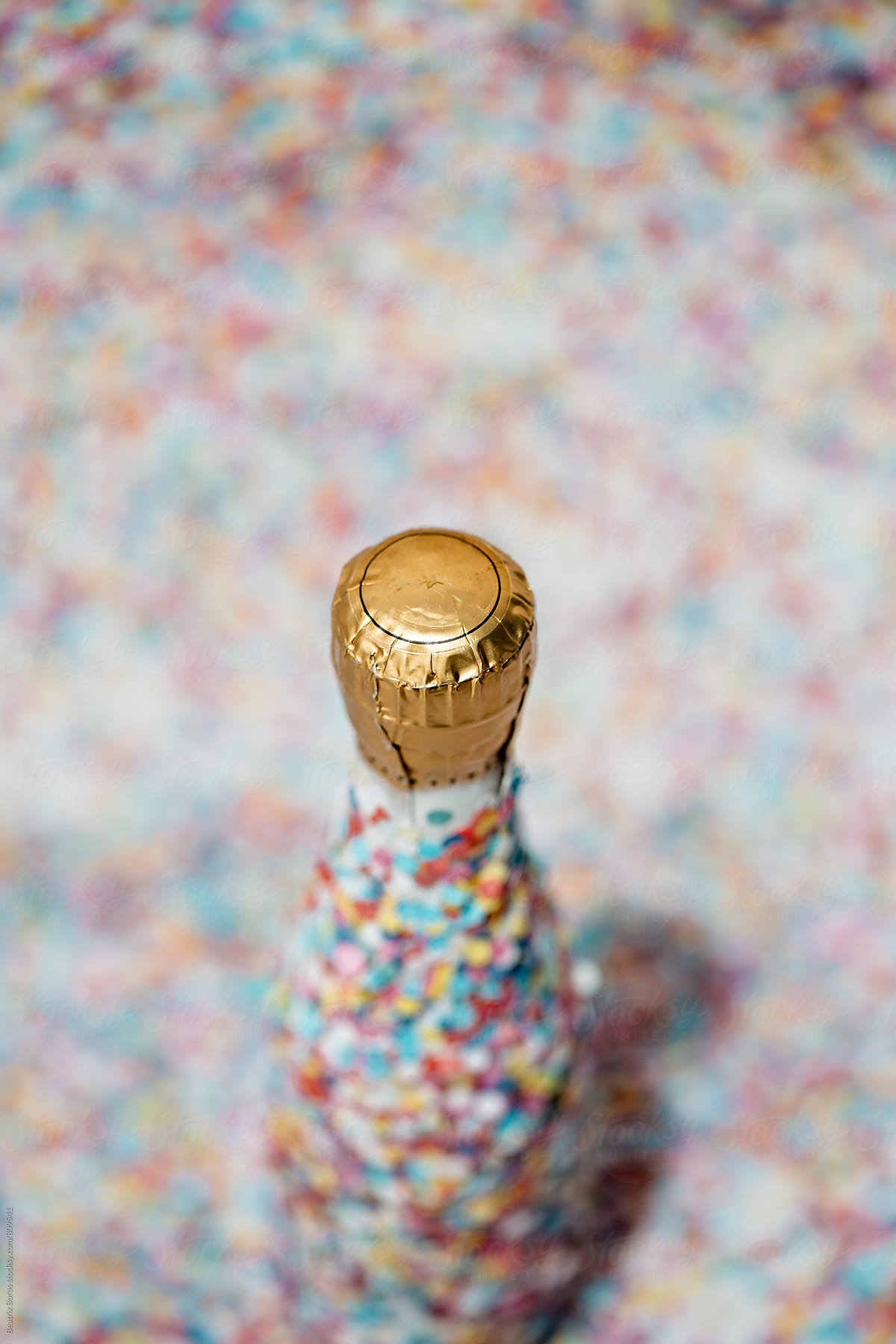 Overhead photo of a Champagne bottle covered with confetti