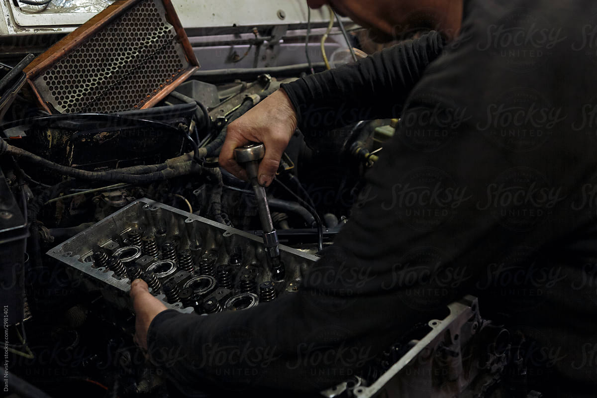 Crop man fixing broken car in workshop