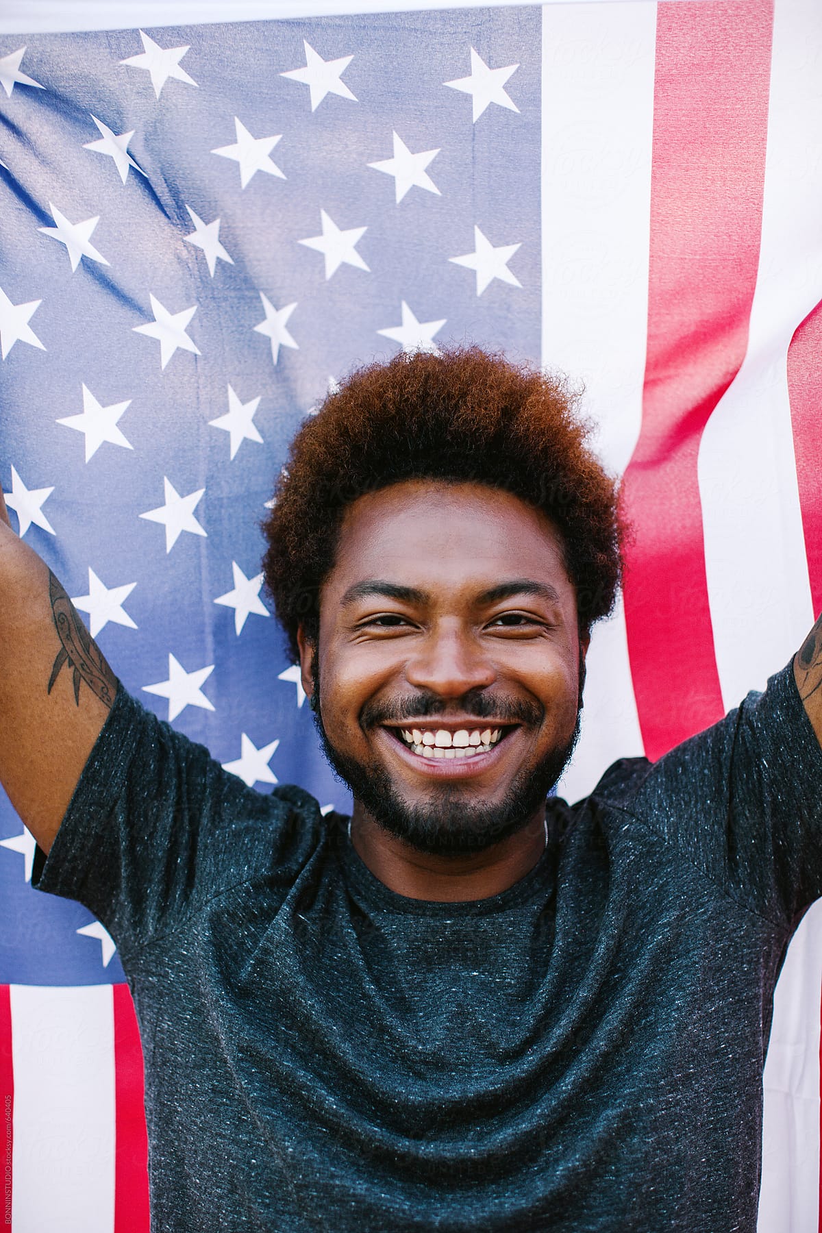 Portrait of a happy black man holding an american flag outdoors.