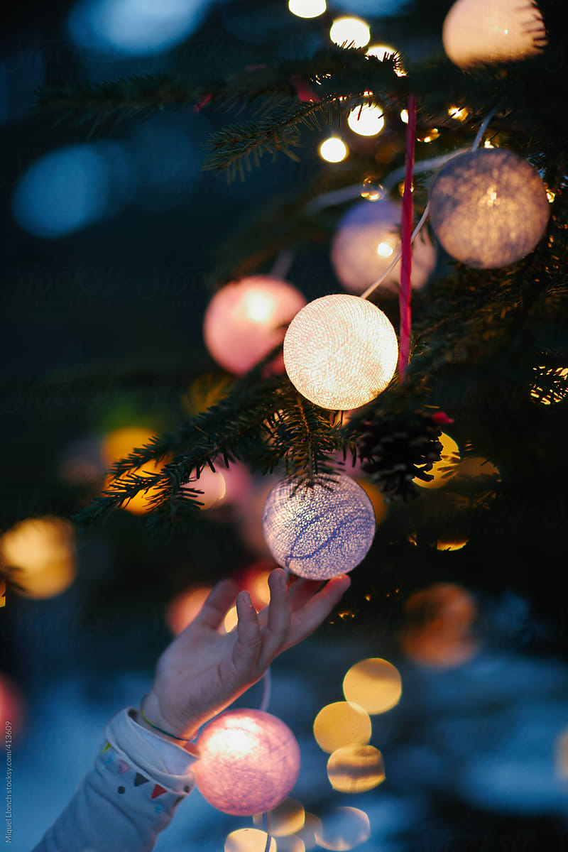 Christmas tree with lit balls and child hand