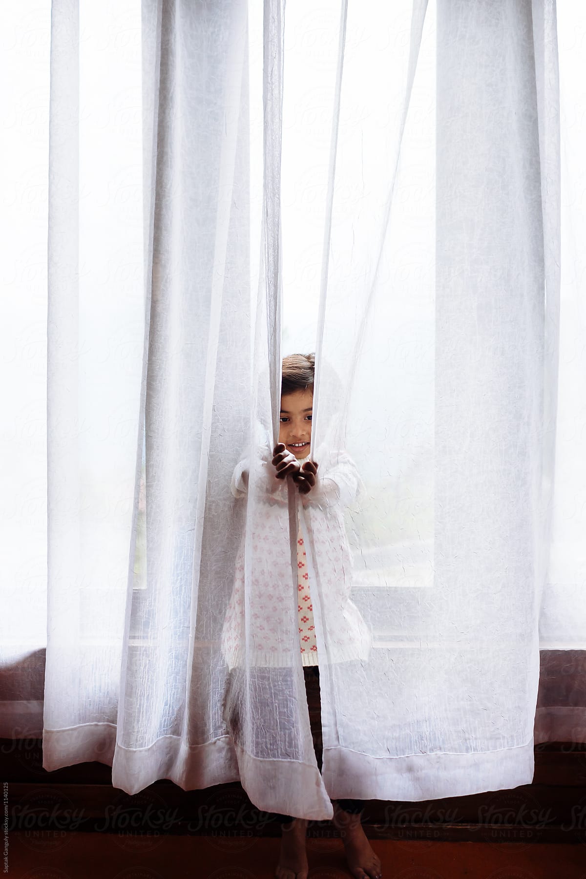 Little girl hiding behind the curtains