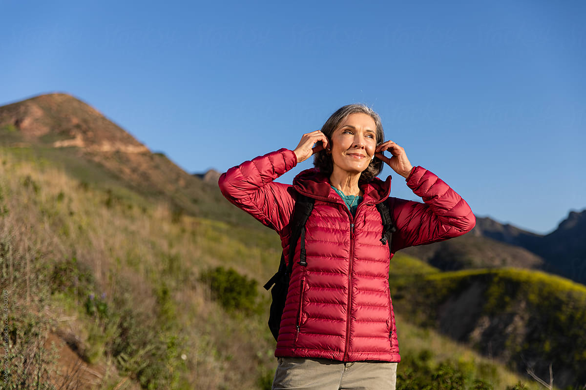 Woman Puts In Headphones While Hiking