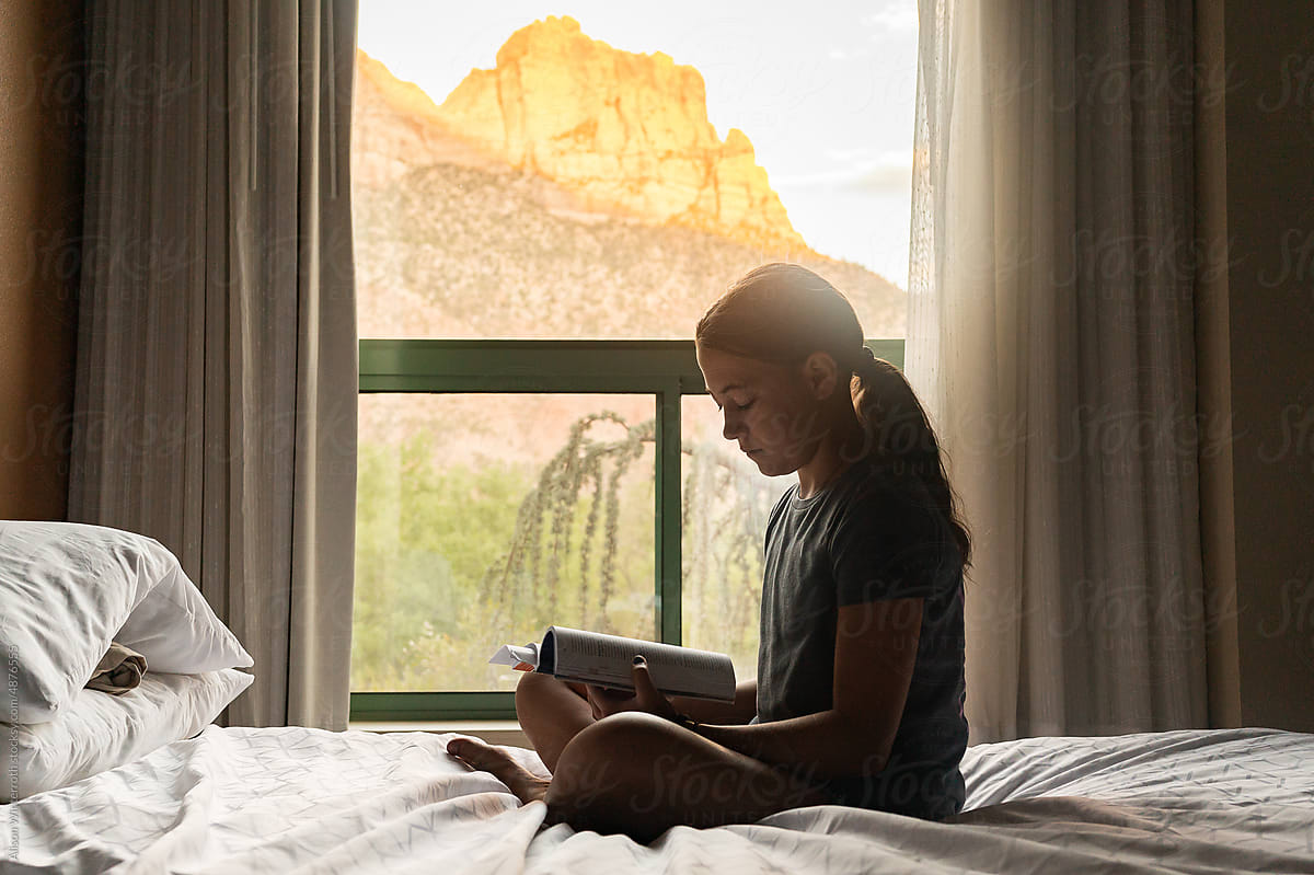 Girl reads in hotel room in mountains