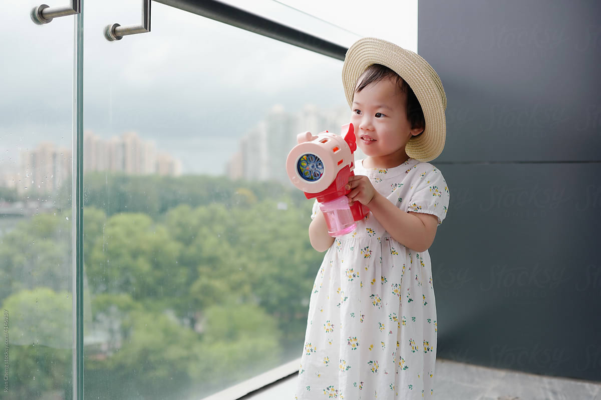Asian baby playing with bubble machine on the balcony