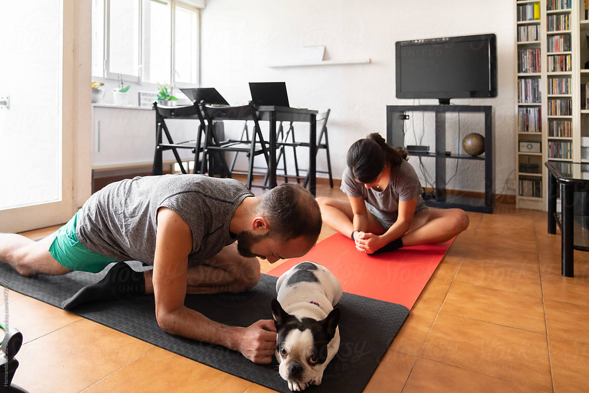 Man And Woman Doing Yoga In Living Room