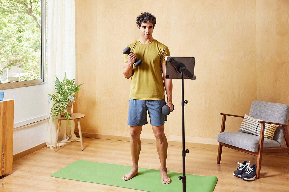 Motivated guy exercising online with dumbbells