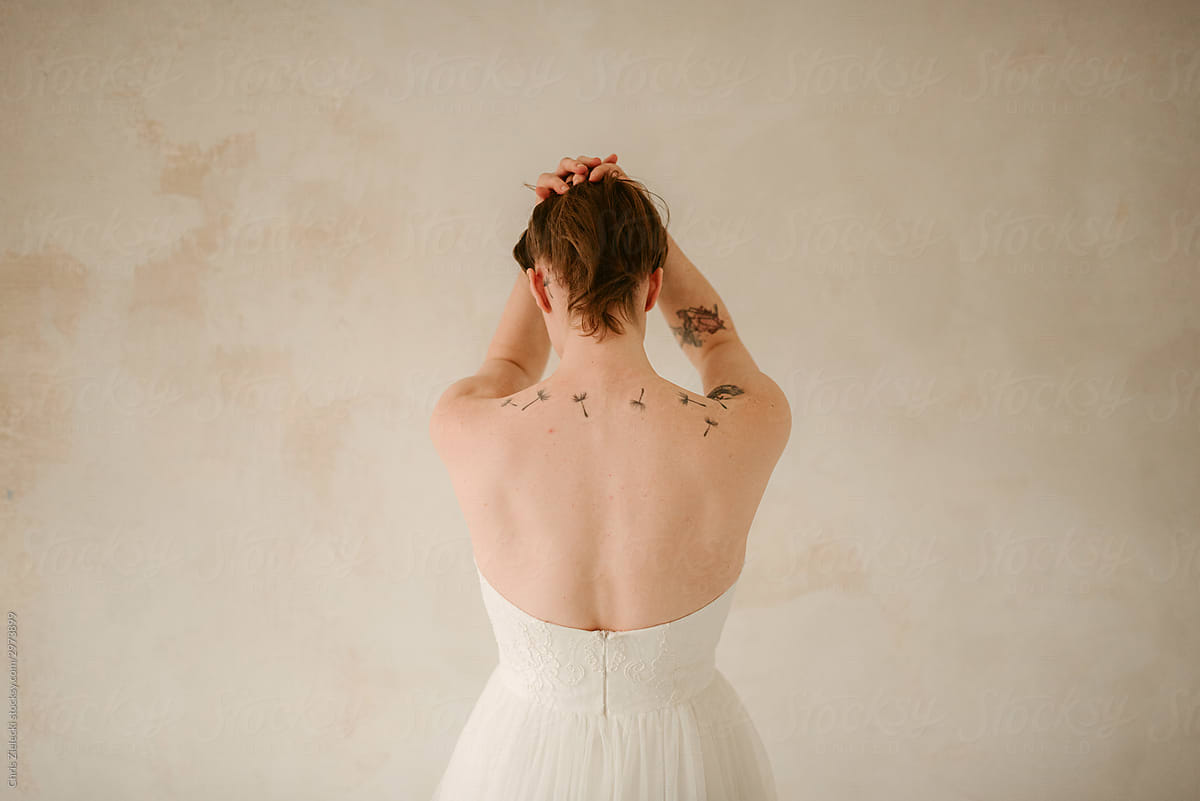 Anonymous bride in wedding dress showing tattoos on back