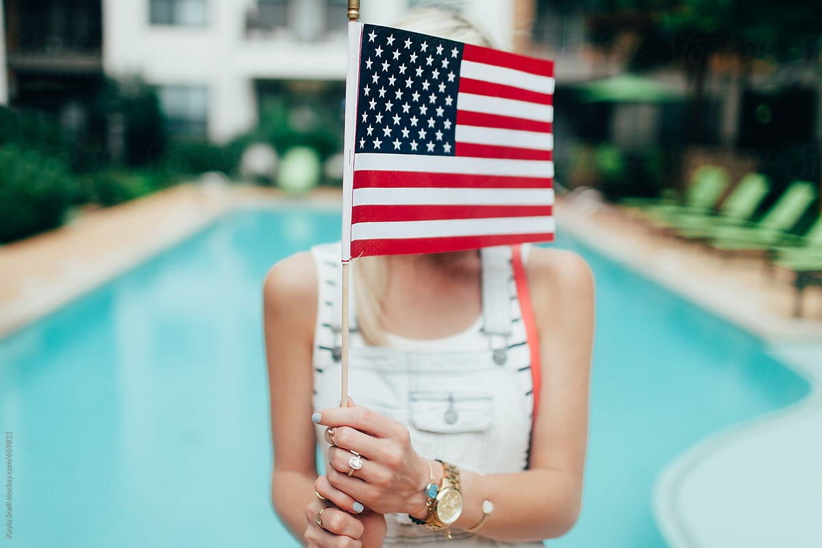 A young blonde woman holding an american flag