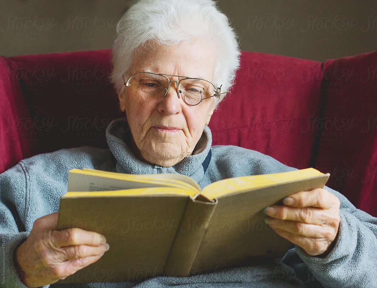 Older woman holding book reading with homemade eyeglasses