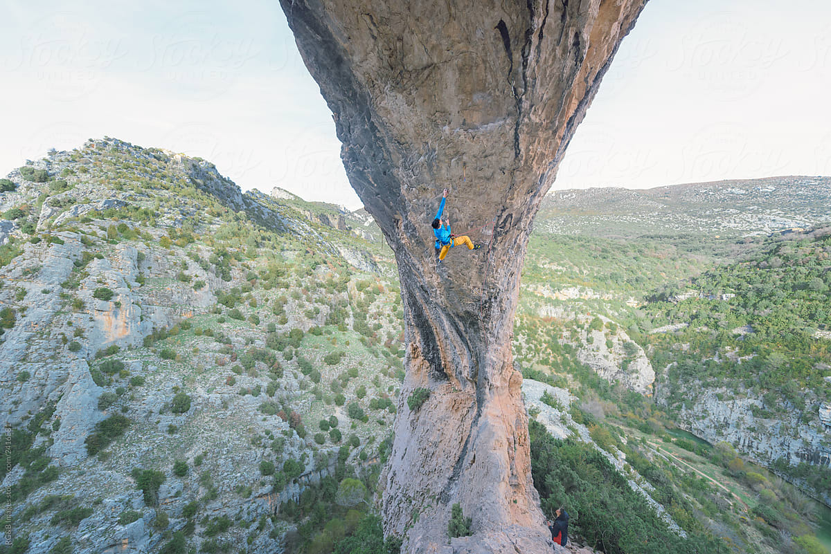 Man sport climbing an overhanging rock arch