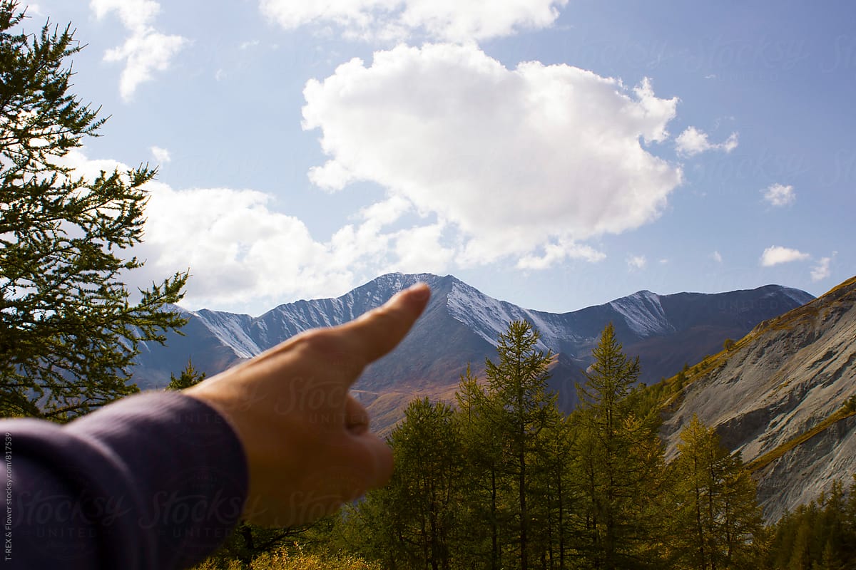 Man\'s hand pointing at puffed cloud in the blue sky