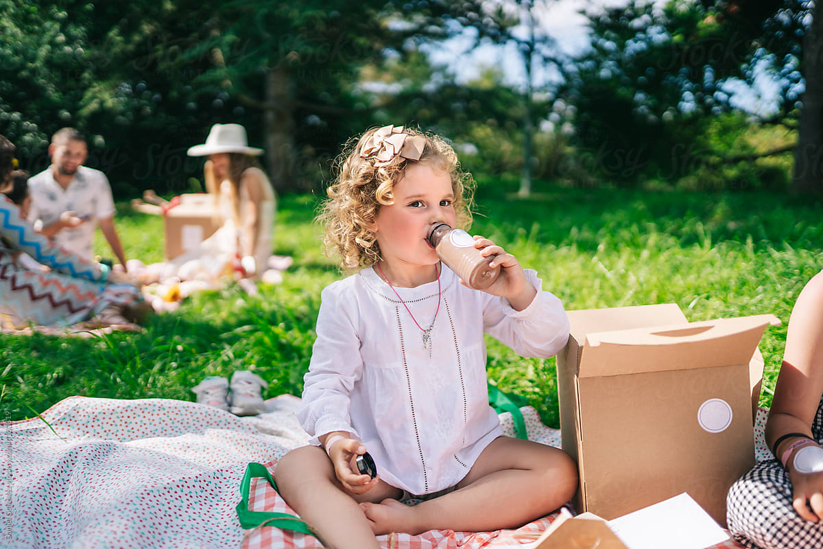 Cute kid drinking beverage during picnic
