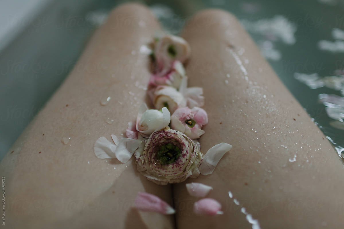 Flowers in between a woman\'s thighs in water.