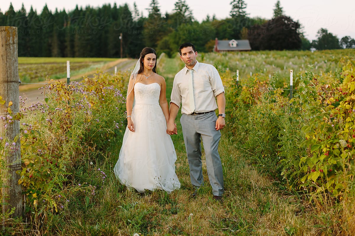 Bride and Groom Standing in Field with Serious Face