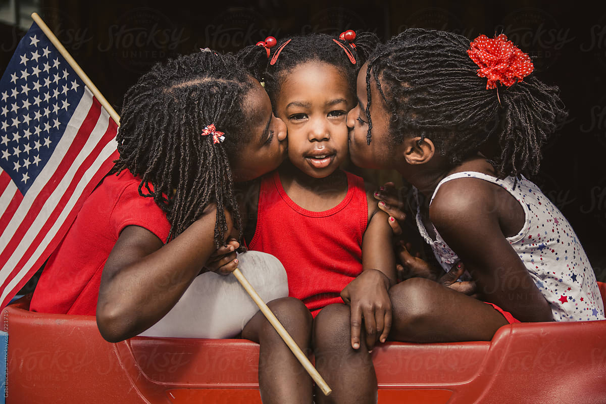Three African-American Girls in USA Flag Colors Outfits Kissing The One in the Middle