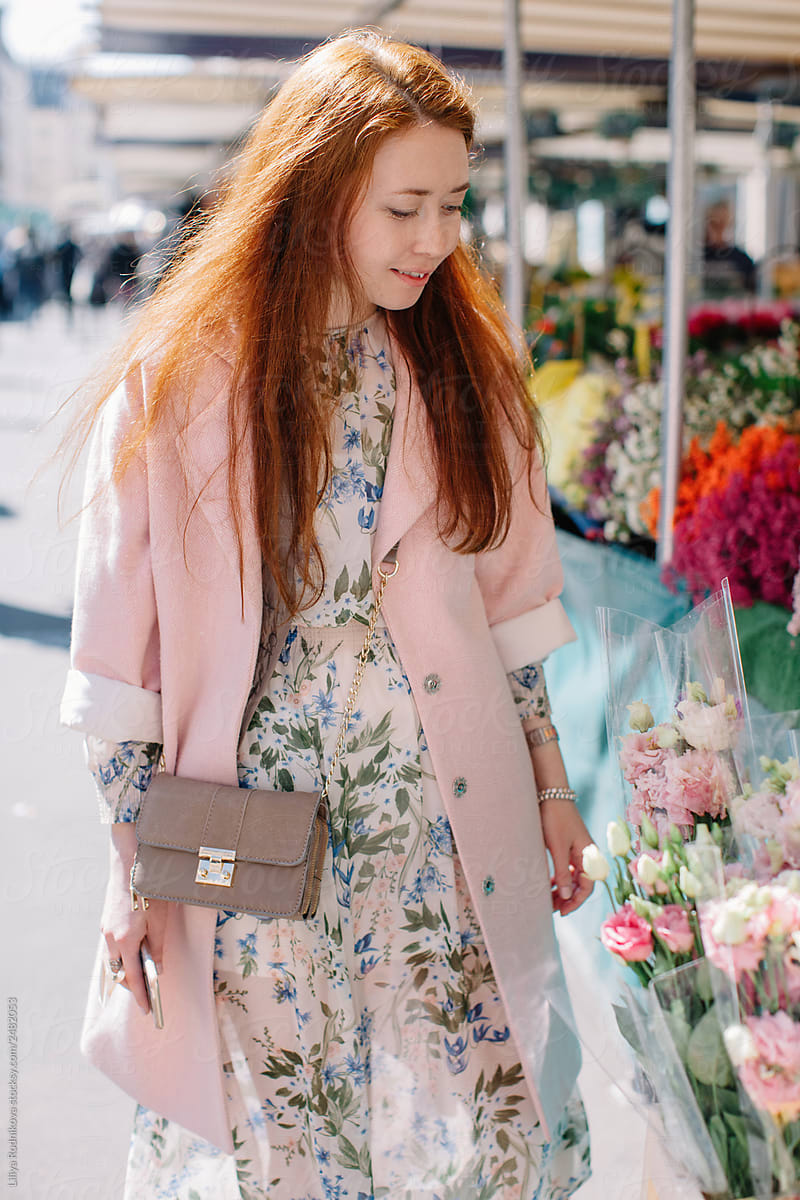 Redhead woman walking by the open market and choosing flowers