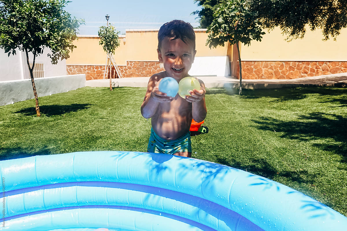 Laughing kid with water balloons in yard