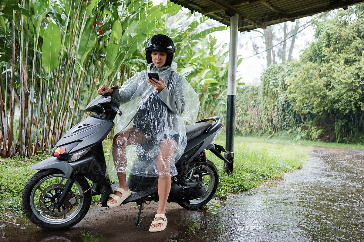 Person Wearing Rain Poncho Sitting on Motorcycle